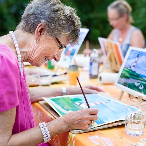 Senior woman smiling while drawing with the group